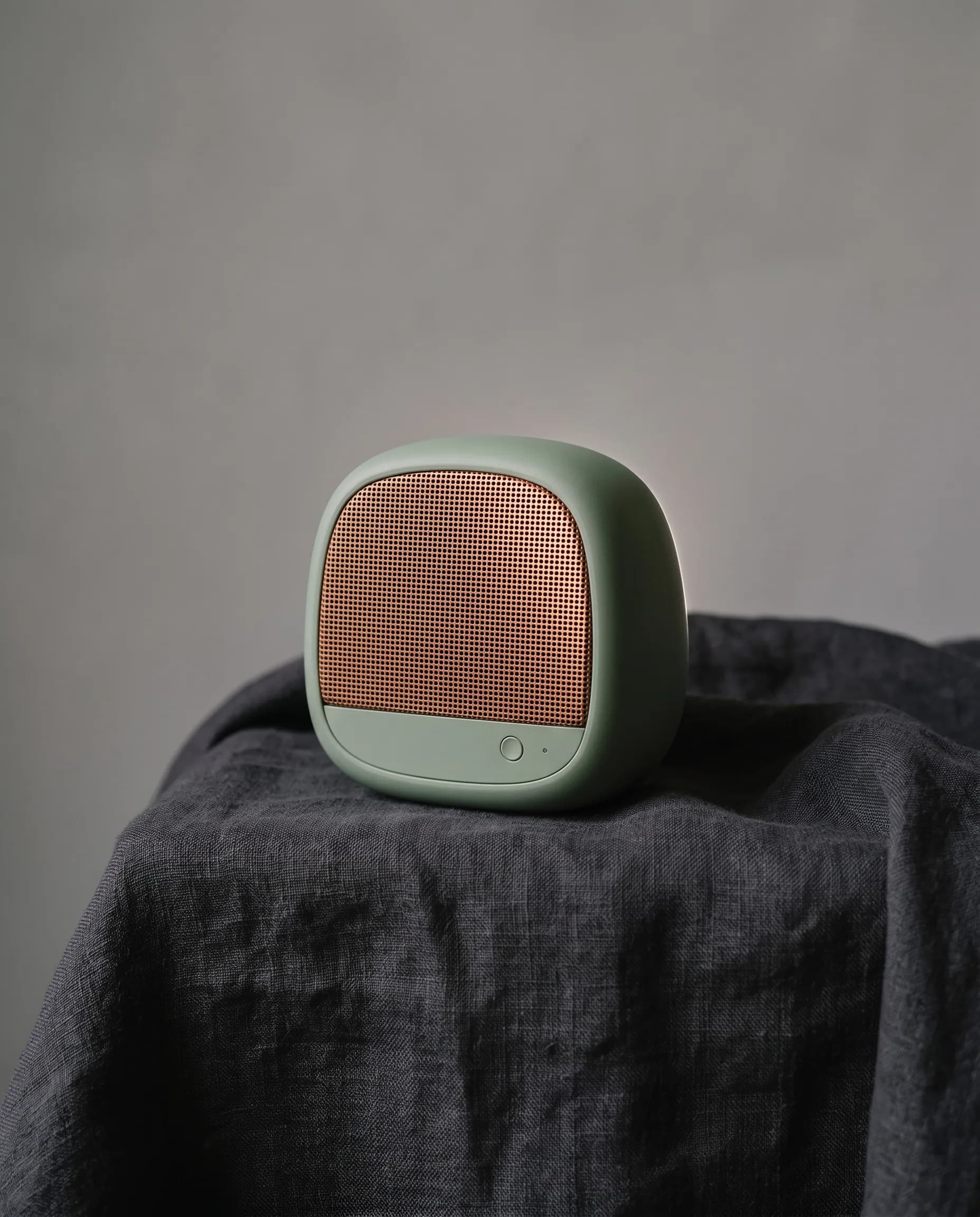 Sage speaker on charcoal linen with light on the copper mesh